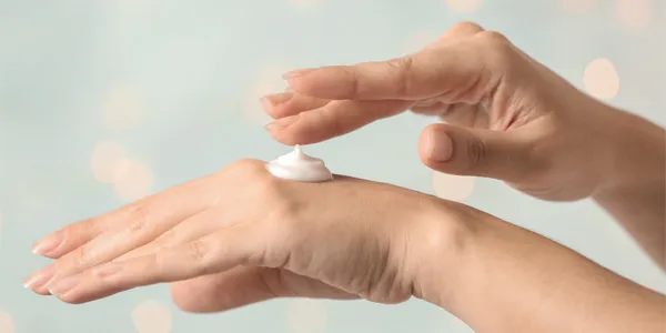 Damskie dłonie, na nich odrobina kremowego serum